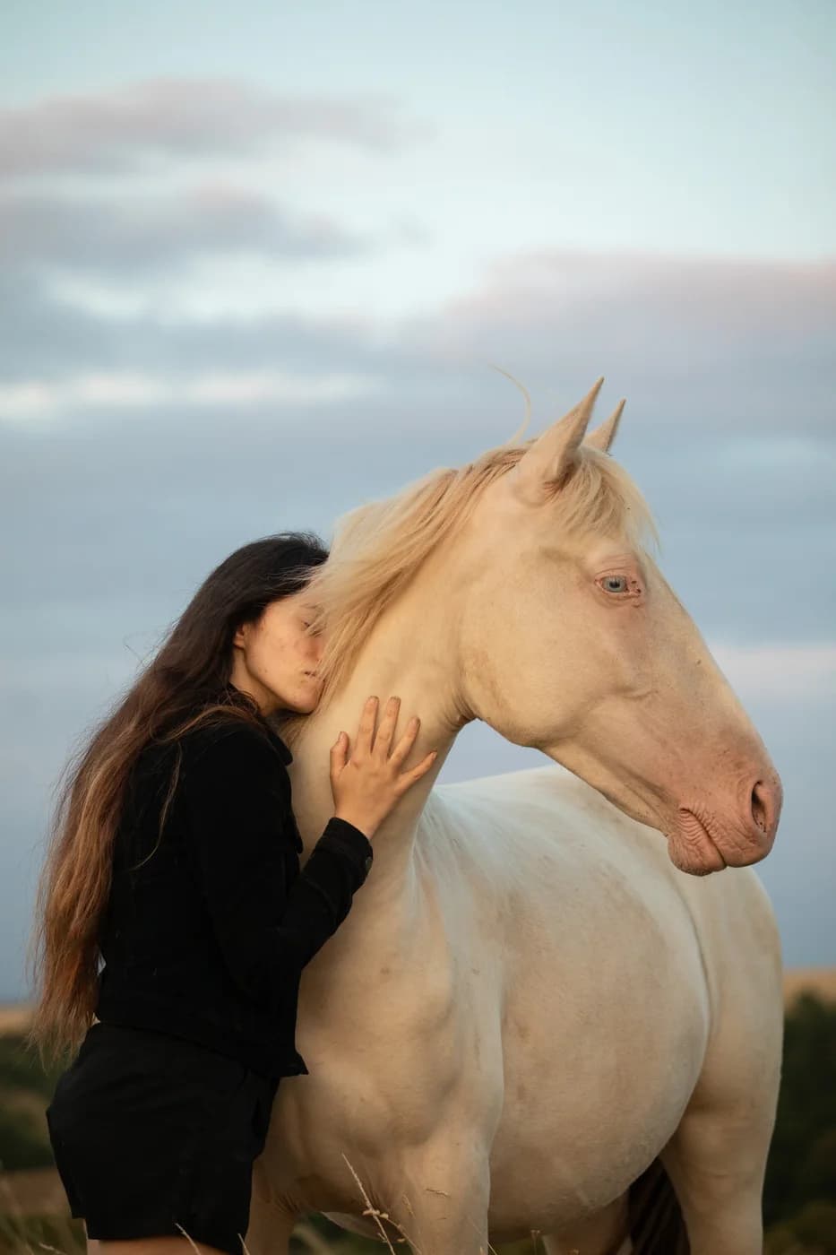 Elia Grimaud with a white horse at twilight